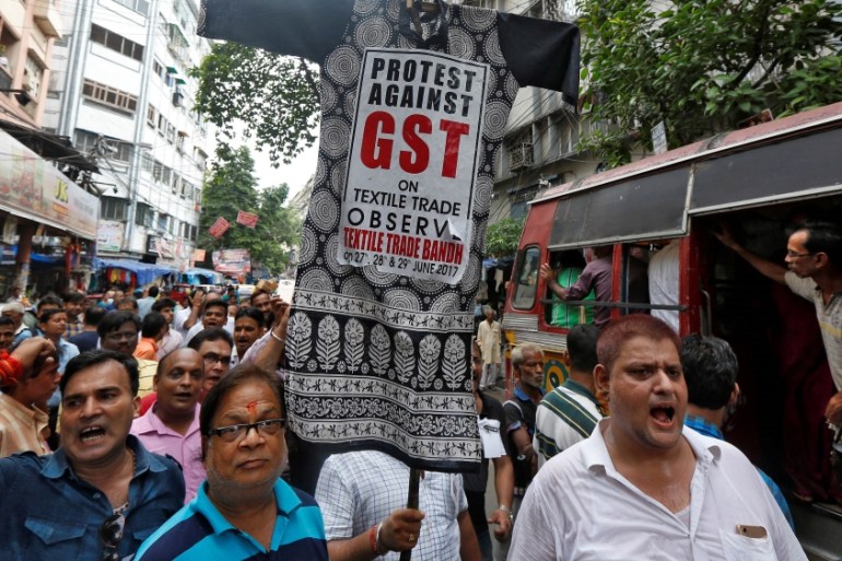 Cloth merchants and workers shout slogans as they carry an effigy depicting Goods and Services Tax (GST) in a market area during a protest rally against implementation of GST on textiles in Kolkata, I