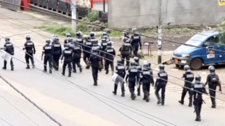 A still image taken from a video shows riot police walk along a street in the English-speaking city of Buea