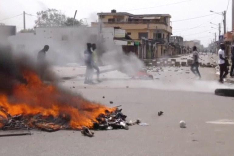 A still image taken from a video shot on October 18, 2017, shows protesters walking past burning tyres in Lome