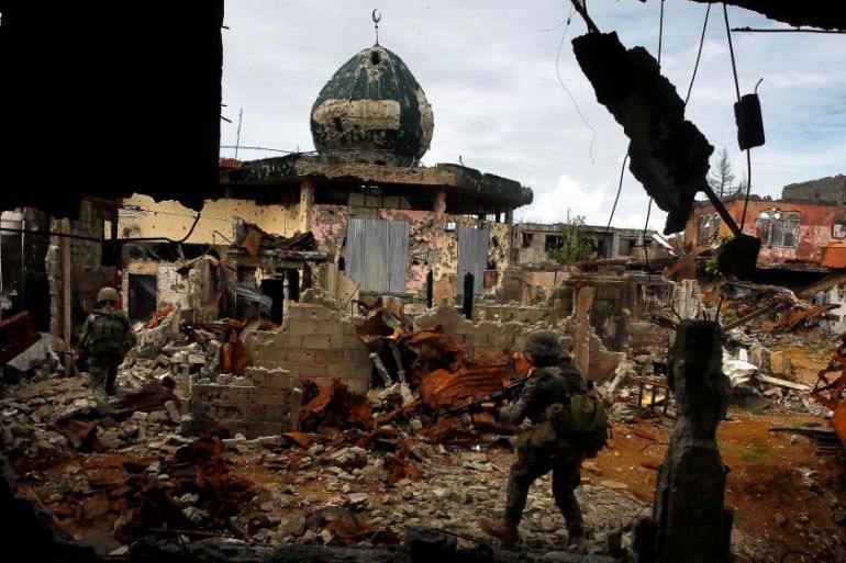 Government soldiers patrol past damaged buildings as troops continue their assault on clearing operations against the pro-IS militant group in Marawi city