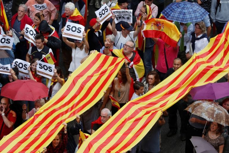 People hold a Catalan flag, known as Senyera, as they march during a demonstration to show support for a unified Spain a day before the banned October 1 independence referendum, in Barcelona