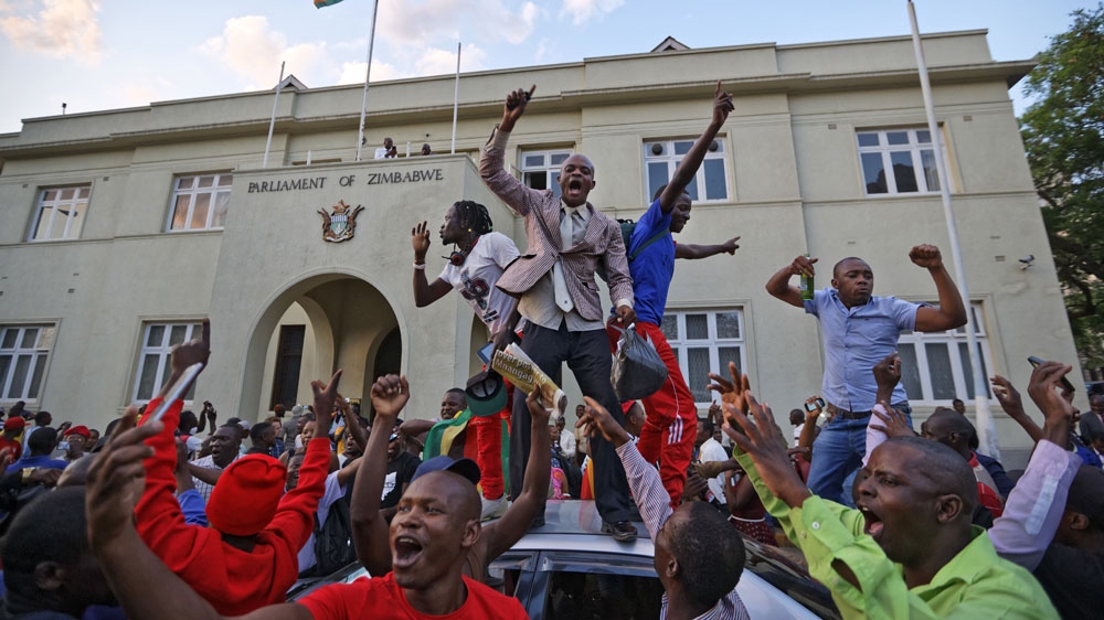 Zimbabweans celebrate outside the parliament building in Harare [Ben Curtis/The Associated Press]