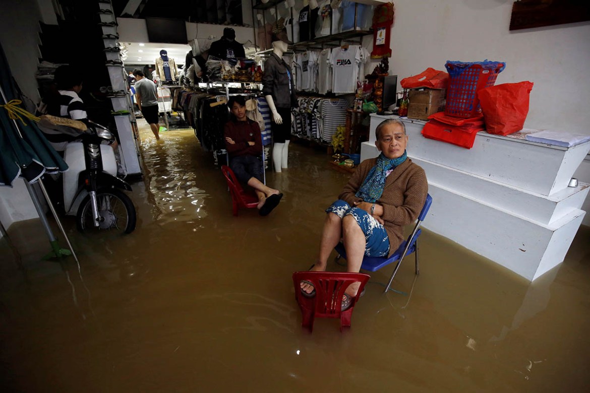 Residents sit on their flooded fashion shop in Hue. REUTERS/Kham