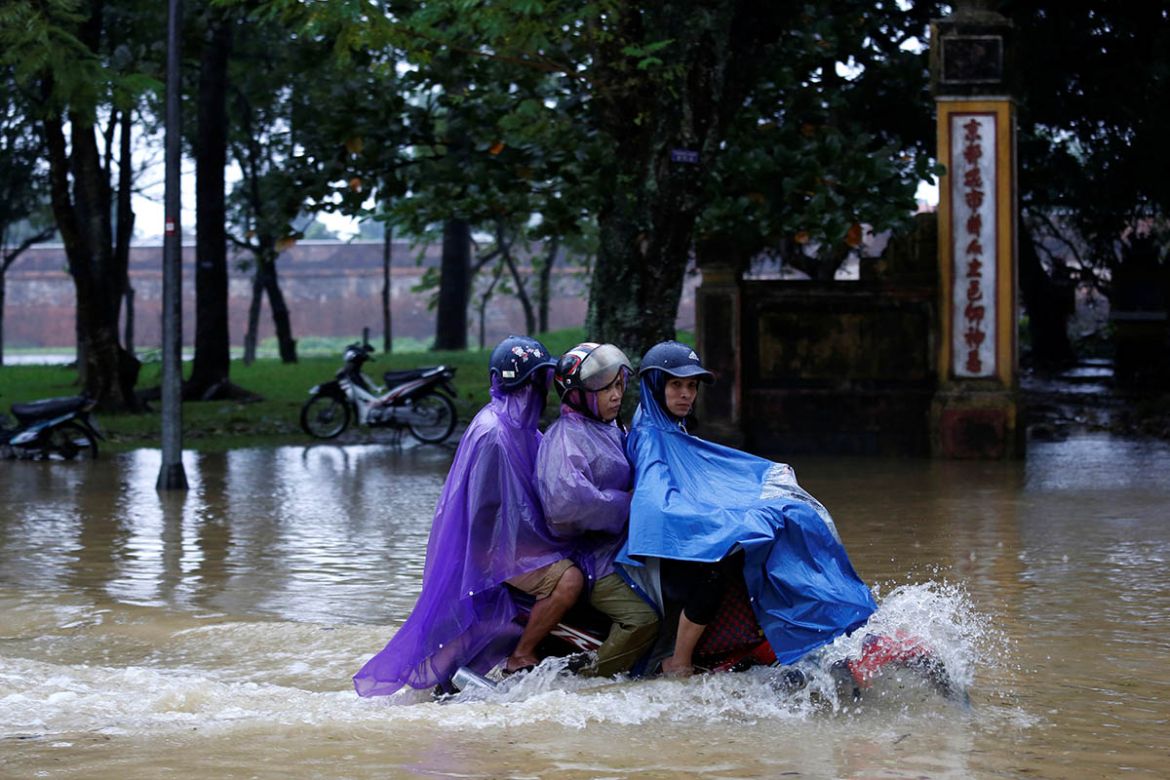 People ride a motorcycle along a flooded road in Hue. REUTERS/Kham