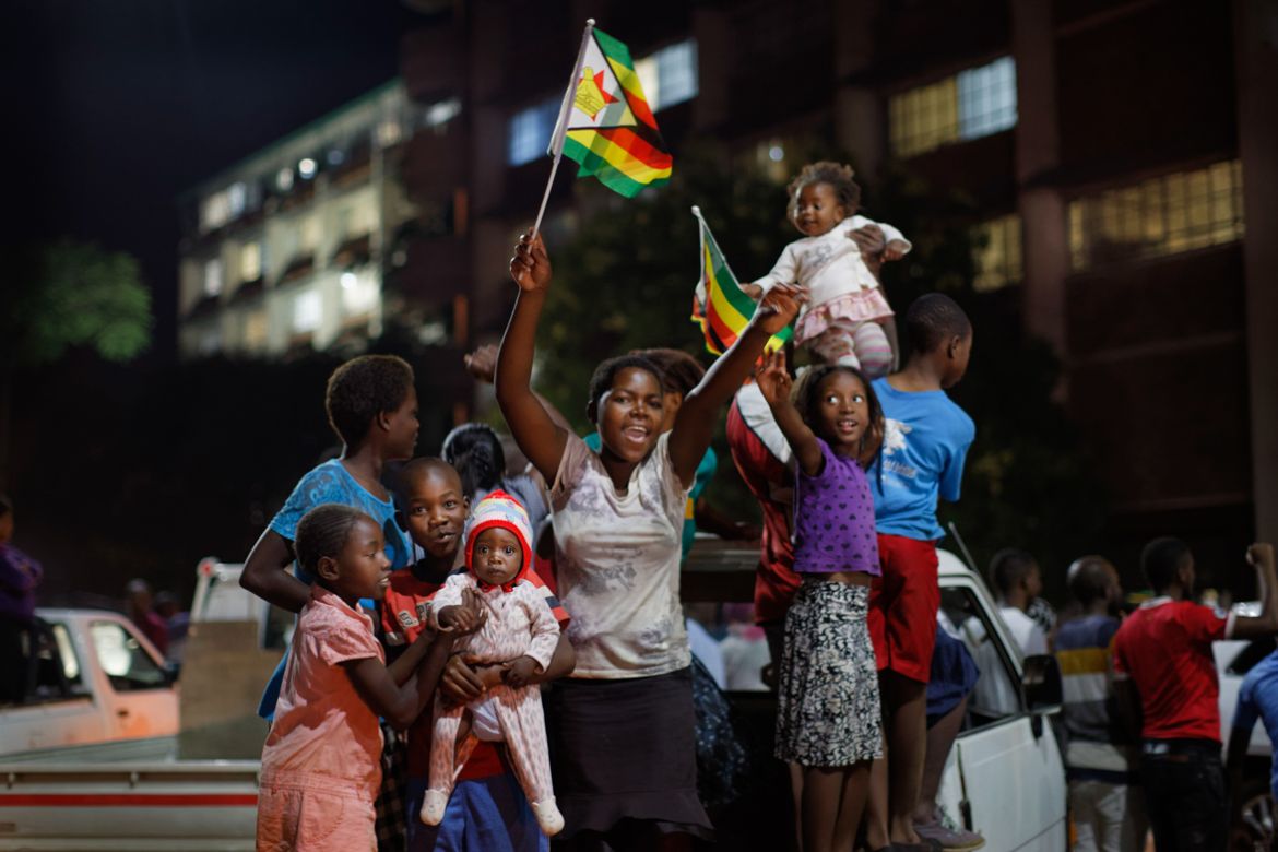 Zimbabweans celebrate at night at an intersection in downtown Harare, Zimbabwe Tuesday, Nov. 21, 2017. Mugabe resigned as president with immediate effect Tuesday after 37 years in power, shortly after