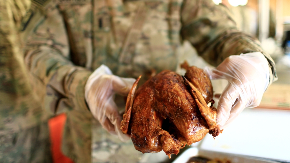 
A US soldier serves turkey to fellow soldiers to celebrate Thanksgiving Day inside the US army base in Qayyara, south of Mosul, Iraq [Thaier Al-Sudani/Reuters]
