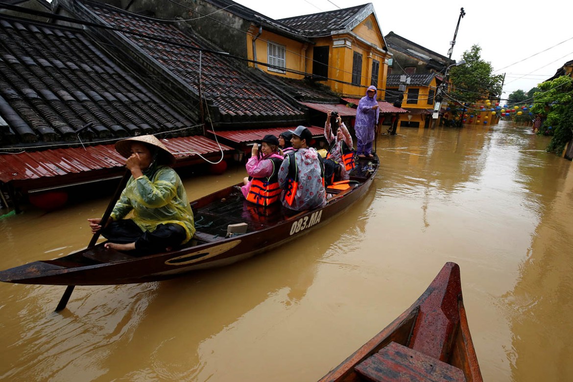 People ride a boat along submerged houses in Hoi An. REUTERS/Kham