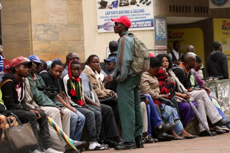 People queue to draw money outside a bank in Harare