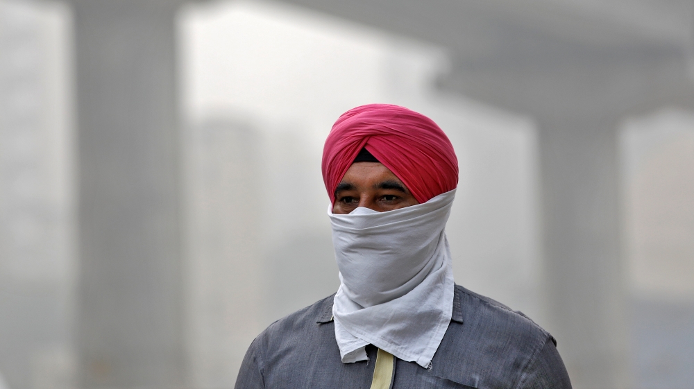 A man covers his face as he walks to work in New Delhi [Saumya Khandelwal/Reuters]