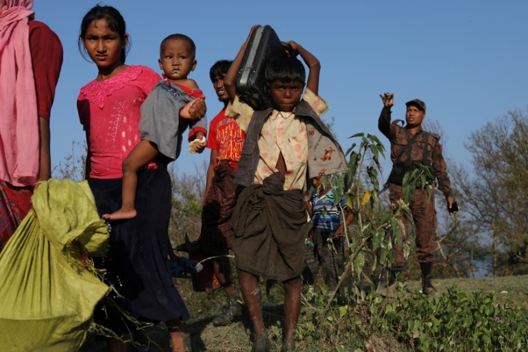 Rohingya refugees carry their belongings after arriving on an improvised raft to the banks of the Naf river in Teknaf