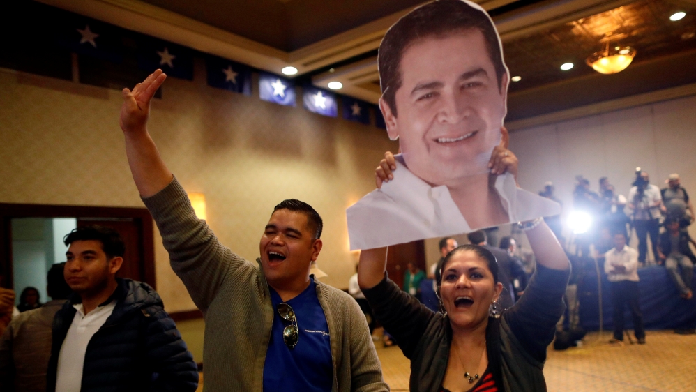 A supporter holds an image of Honduras President Juan Orlando Hernandez during a rally after the first official presidential election results were released [Edgard Garrido/Reuters]