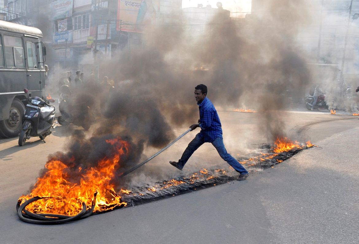 A demonstrator drags burning tyres during a day-long strike to protest against the killing of Sudip Datta Bhowmik, a local journalist, who according to local media was shot dead by a Tripura State Rif
