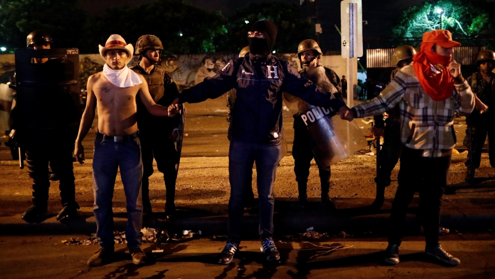 Supporters of Salvador Nasralla stand in front of riot police while they wait for official presidential election results outside a Supreme Electoral Tribunal building in Tegucigalpa [Edgard Garrido/Reuters] 