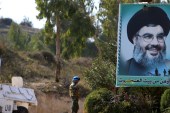 A peacekeeper of the UN Interim Force in Lebanon stands near a poster depicting Lebanon's Hezbollah leader Sayyed Hassan Nasrallah in southern Lebanon [Reuters/Ali Hashisho]