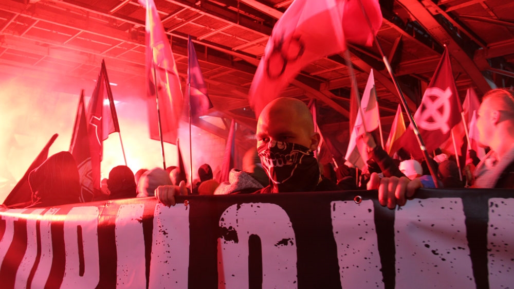 A member of the far right carries a banner at the march [Agnieszka Pikulicka-Wilczewska/Al Jazeera]