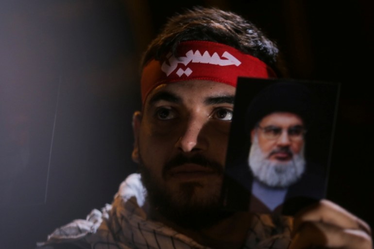 A Lebanon''s Hezbollah supporter holds a photograph of leader Sayyed Hassan Nasrallah during his address via a video screen during a ceremony of the latest day of Ashoura in Beirut