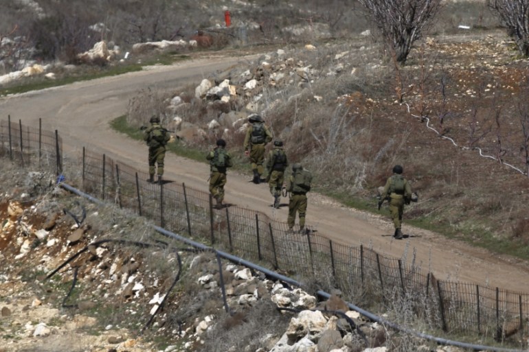 Israeli soldiers walk towards the border with Syria, near the Druze village of Majdal Shams in the Israeli-occupied Golan Heights