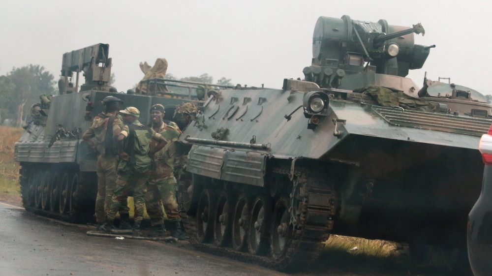 Soldiers on Tuesday stand beside military vehicles just outside Harare, [Philimon Bulawayo/Reuters]