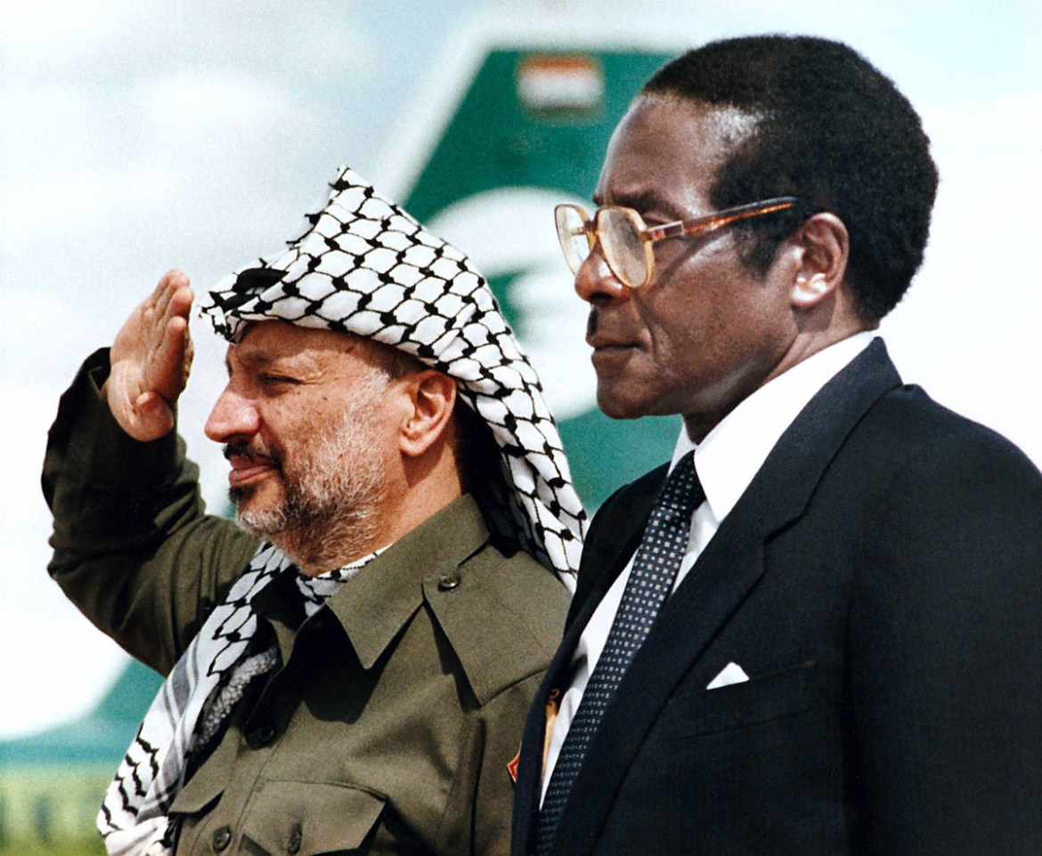 Zimbabwean Prime Minister Robert Mugabe, right, stands next to Chairman of the PLU Yasser Arafat as he salutes after arriving at Harare Airport, Zimbabwe, on Tuesday, April 14, 1987, to attend a meeti