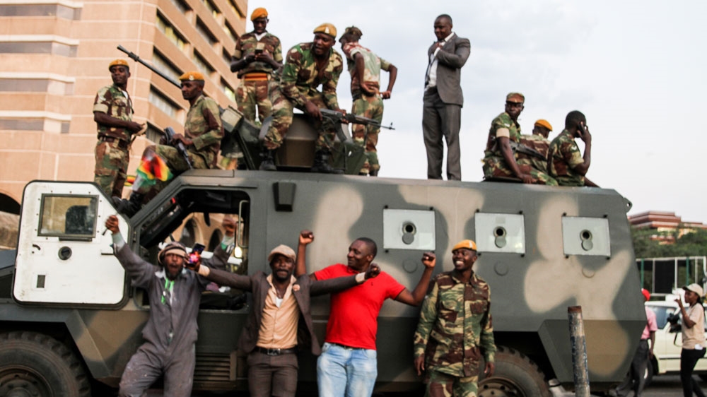 Soldiers and civilians pose for pictures outside the ZANU-PF headquarters [Tendai Marima/Al Jazeera] [Al Jazeera]