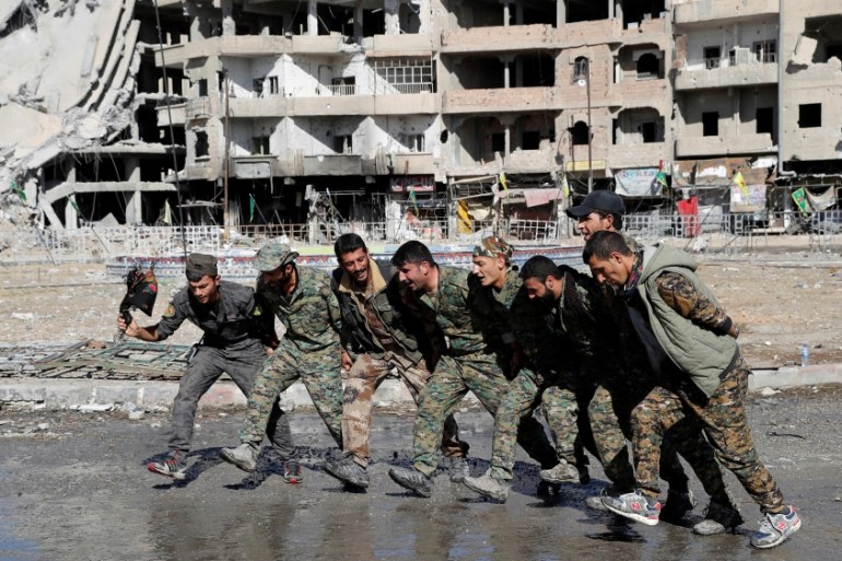 Syrian Democratic Forces fighters dance along street in Raqqa