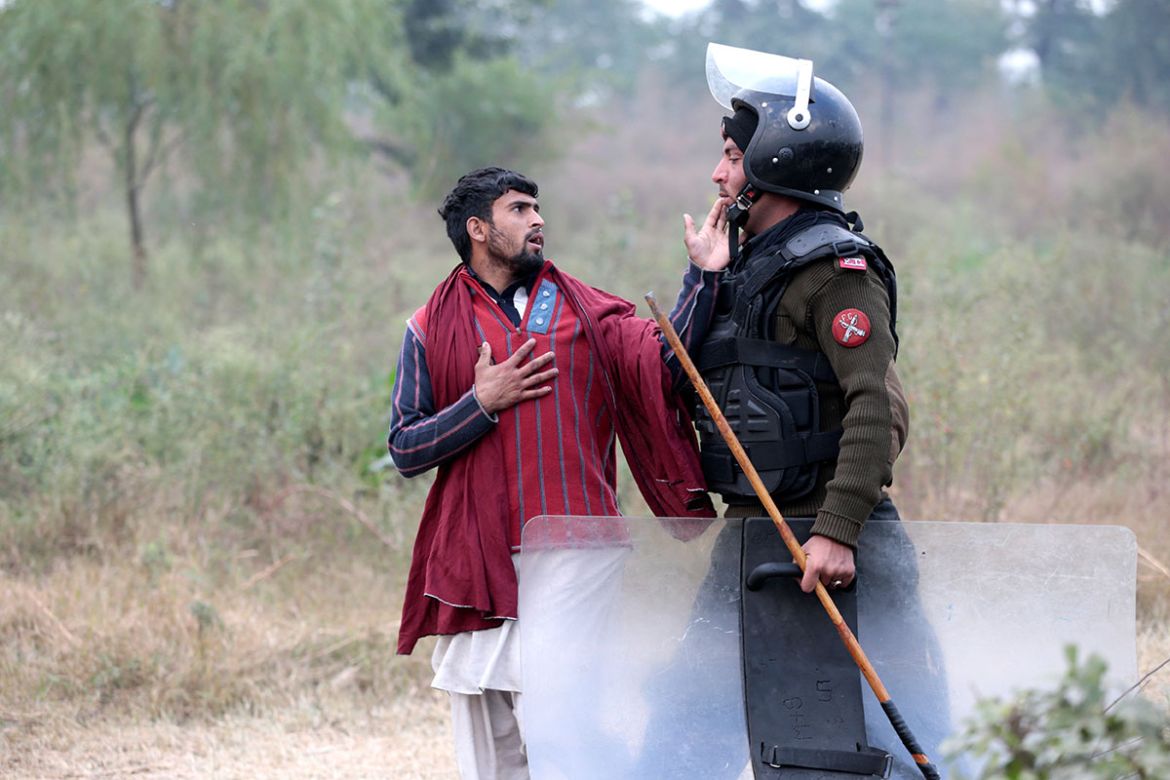 A demonstrator detained by a policeman gestures near the Faizabad junction in Islamabad, Pakistan November 25, 2017. REUTERS/Caren Firouz