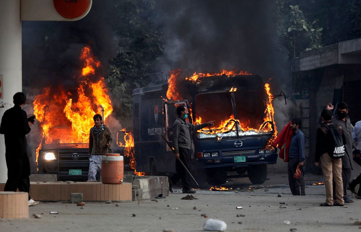 Pakistani protesters gather next to burning police vehicles after setting on fire them during a clash in Islamabad, Pakistan, Saturday, Nov. 25, 2017. Pakistani police have launched an operation to cl