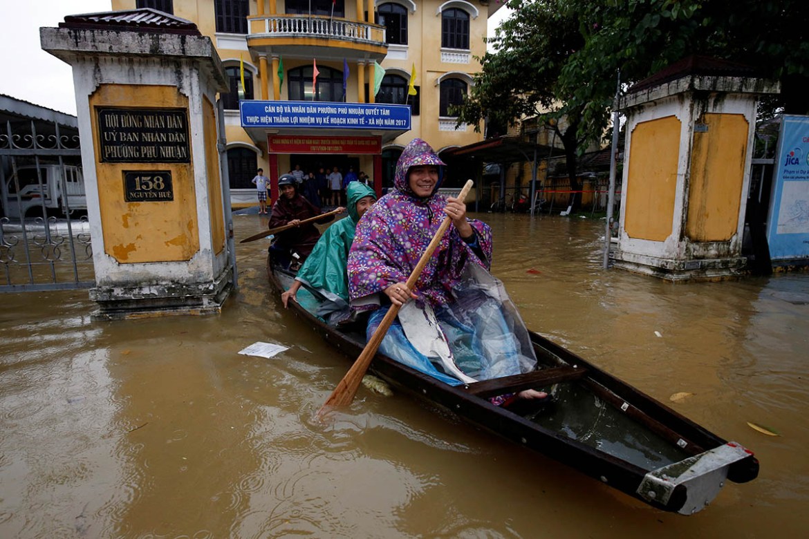 Officials sail a boat out of a submerged local government building in Hue. REUTERS/Kham