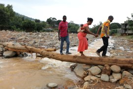 A man helps a woman cross a log bridge after the flash flood washed away a concrete bridge at Pentagon, in Freetown August 18, 2017. REUTERS/Afolabi Sotunde TPX IMAGES OF THE DAY