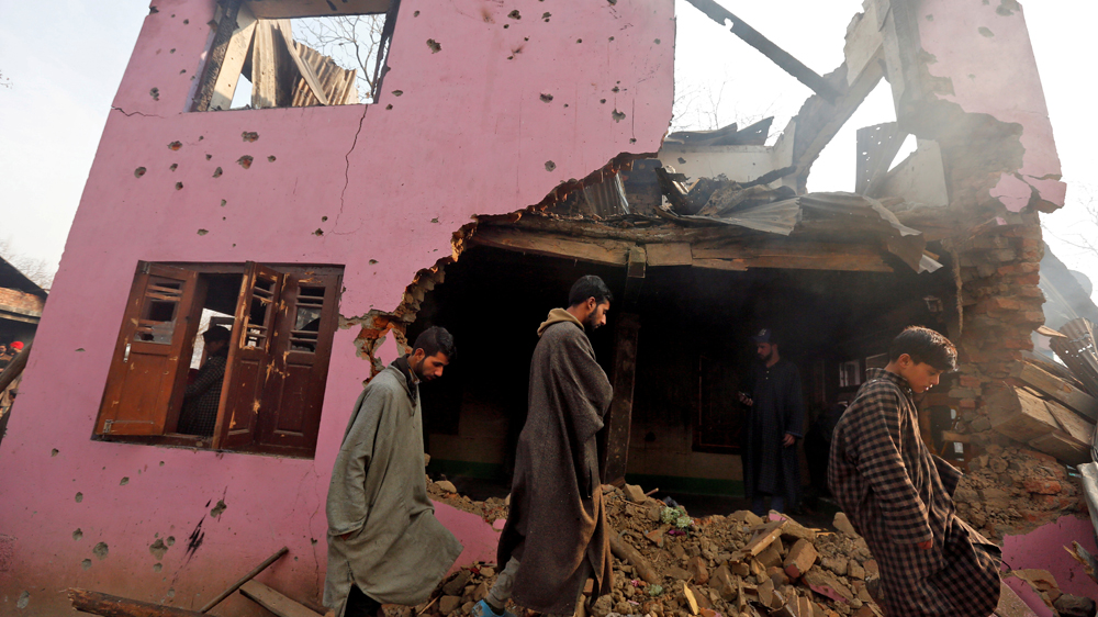 People walk on the rubble of a house damaged in the gun battle [Danish Ismail/Reuters]