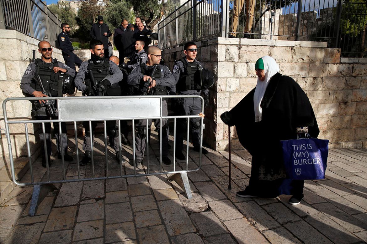 A Palestinian woman walks past Israeli policemen standing guard during a protest following U.S. President Donald Trump''s announcement that he has recognized Jerusalem as Israel''s capital, near Damascu