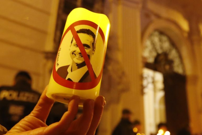 A demonstrator holds a candle with a picture of FPOe head Strache in a protest demanding no government participation for the far right in Vienna