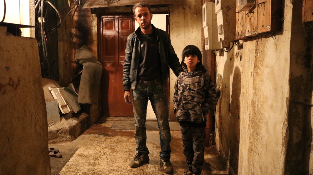 Rami Saaf and his nine-year-old son, Jihad, stand outside their home, where water leaks onto wires [Lisa Khoury/Al Jazeera]