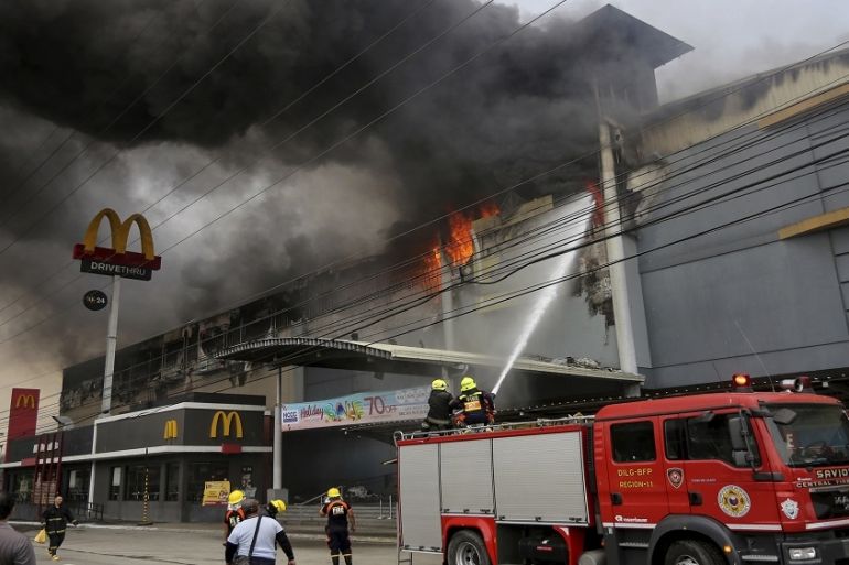 Firemen battle a fire that rages at a shopping mall, Saturday, Dec. 23, 2017, in Davao city, southern Philippines (AP Photo/Manman Dejeto)