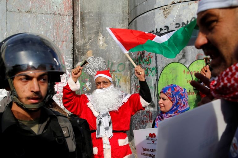 Palestinian dressed as Santa Claus stands next to an Israeli border police during clashes in the West Bank city of Bethlehem