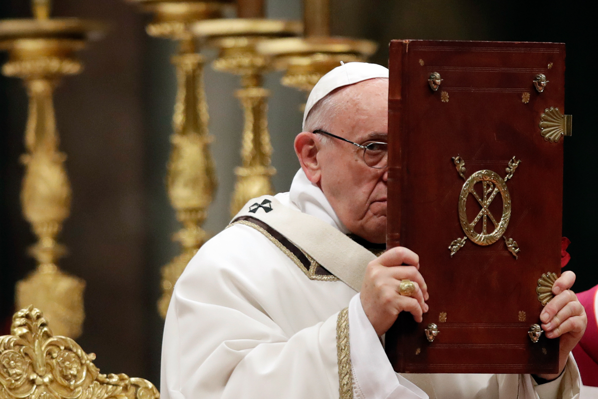 Pope Francis holds the book of the Gospel as he celebrates the Christmas Eve Mass in St. Peter's Basilica at the Vatican [File: Alessandra Tarantino/AP Photo]