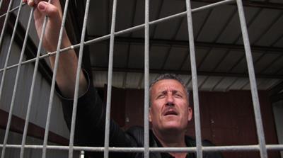Ahed's father Bassem Tamimi stands inside a waiting cell ahead of the verdict in his trial at Israel's Ofer military court near the West Bank city of Ramallah on May 20, 2012 [AP/Diaa Hadid]