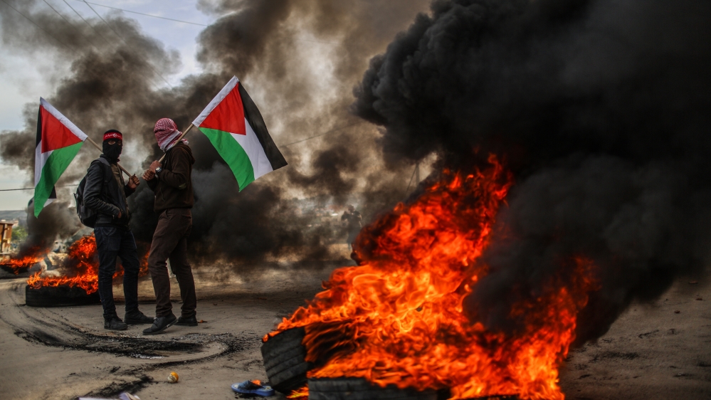 Palestinian protesters burn tyres and hold Palestinian flags in Gaza, in protest of the US decision to recognise Jerusalem as Israel's capital [Anadolu Agency]