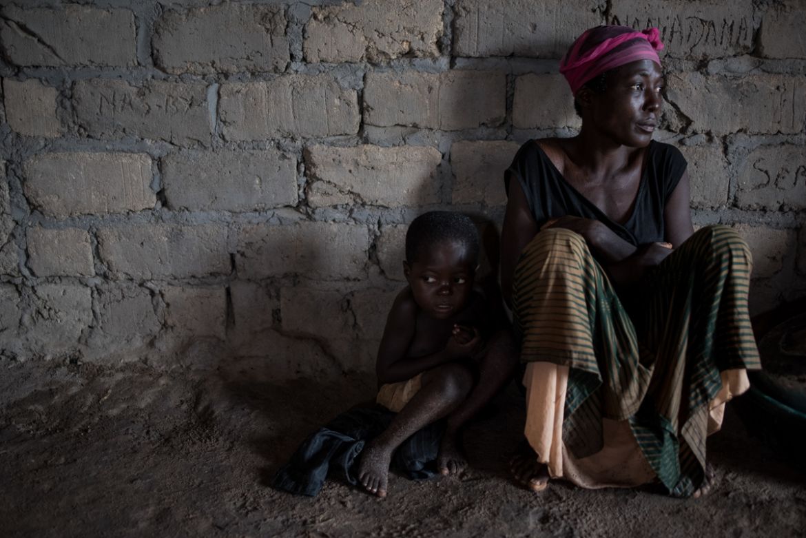 Liliane Mwayuma, 36, and her 3-year-old son Yvon shelter in the Church of Light. Children in the church sleep rough on wet soil, thinly covered by empty sacks of sugar. Their raw coughs are muffled b