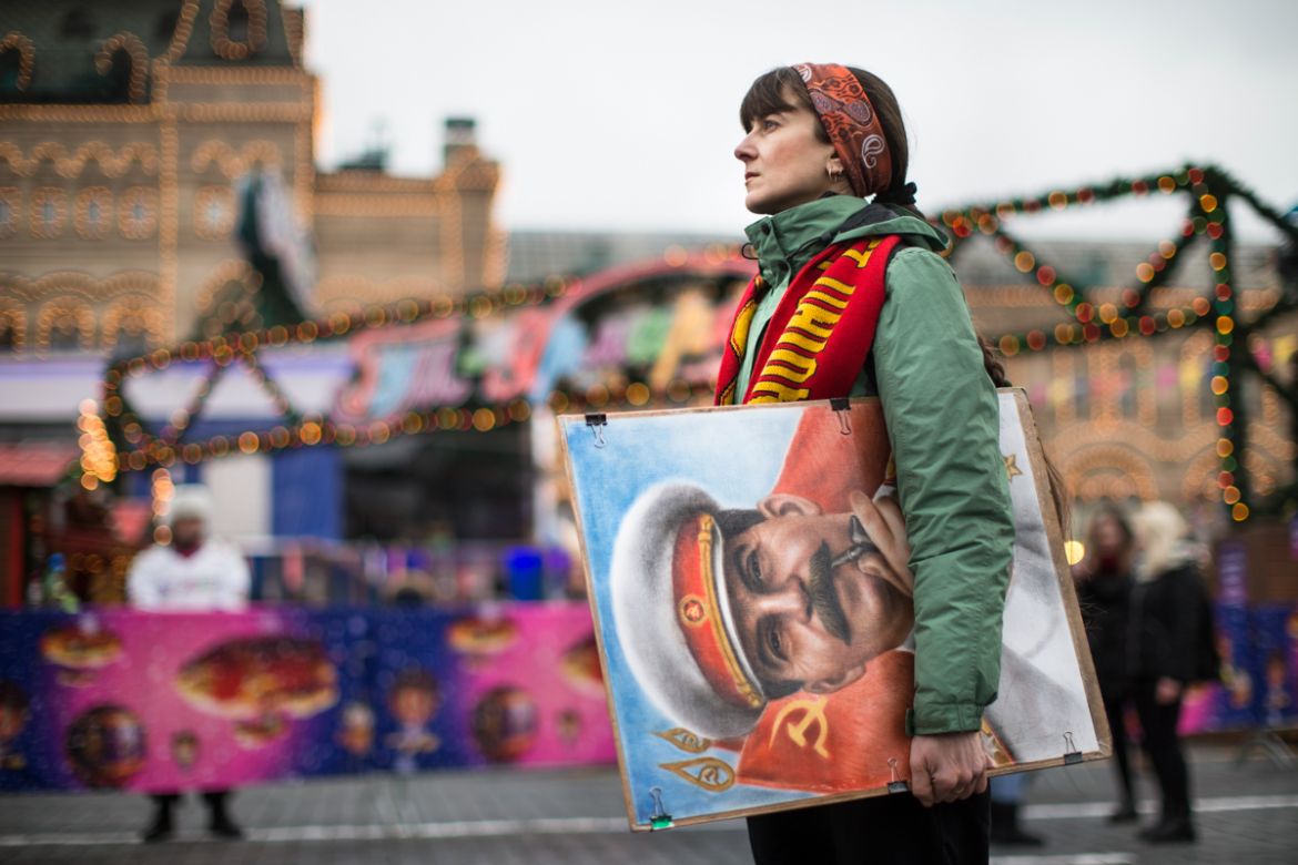 An artist holds a portrait of former Soviet leader Josef Stalin outside the GUM, State Department store decorated with New Year and Christmas illumination in Moscow''s Red Square, Thursday, Dec. 21, 20