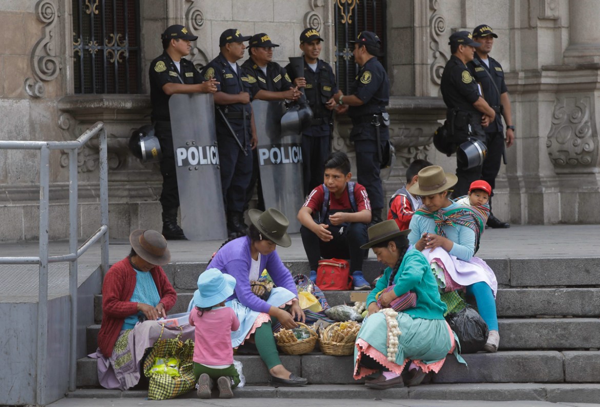 Women prepare to sell candy on the steps of the government palace where police stand guard and impeachment proceedings against Peru''s President Pedro Pablo Kuczynski are going on in Lima, Peru, Wednes