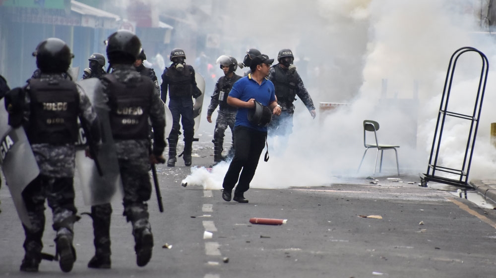A man walks away from tear gas as supporters of Salvador Nasralla, then-presidential candidate for the Opposition Alliance Against the Dictatorship, clash with police during a December protest caused by the delayed vote count for the presidential election in San Pedro Sula [File: Moises Ayala/Reuters] 