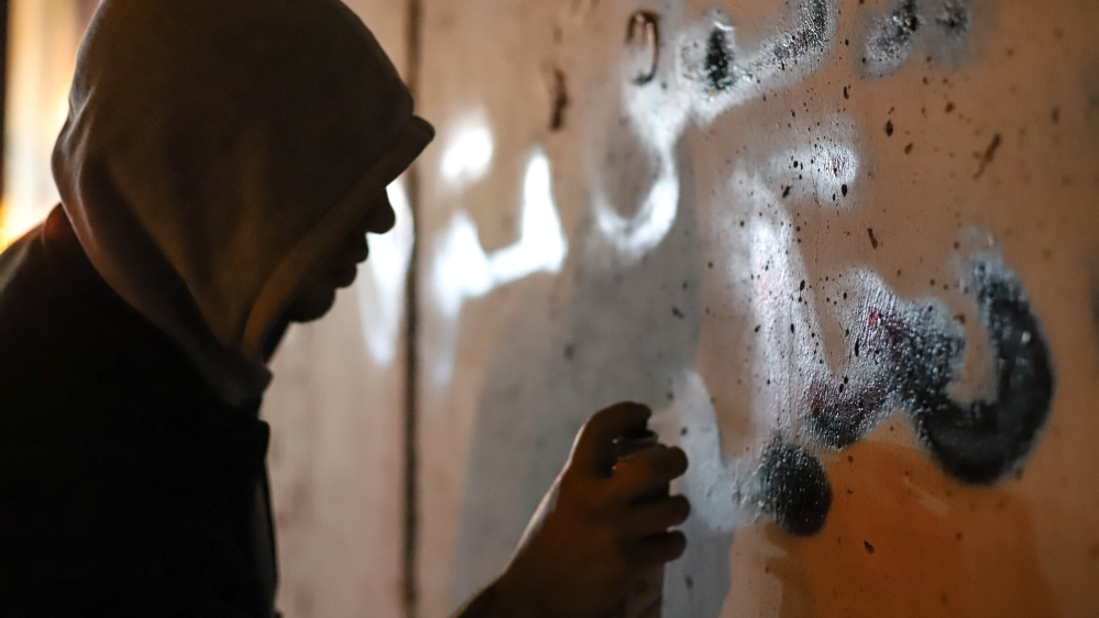 
A Palestinian defaces graffiti near Bethlehem [Jaclynn Ashly/Al Jazeera]
