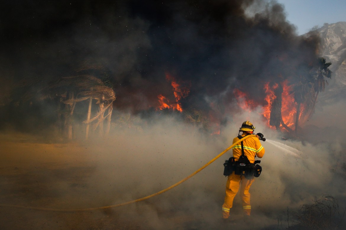 A firefighter battles a wildfire at Faria State Beach in Ventura, Southern California. The wind-swept blazes have forced tens of thousands of evacuations and destroyed dozens of homes. [Jae C. Hong/AP
