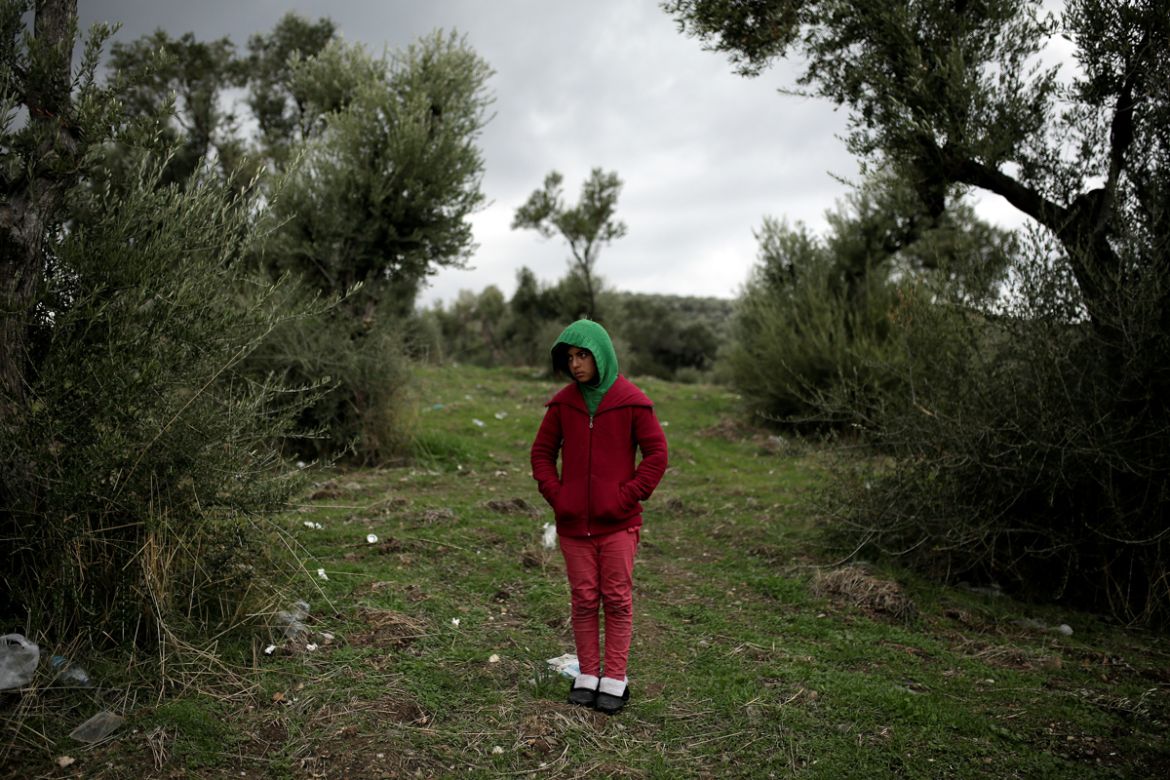 Arebi, a Syrian refugee girl, stands at a makeshift camp for refugees and migrants next to the Moria camp on the island of Lesbos, Greece. The hundreds sleeping in the woods are among more than 8,500