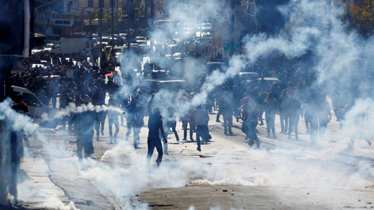 Palestinian demonstrators react to tear gas fired by Israeli troops