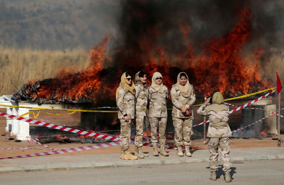 Members of the anti narcotics force pose for a picture as drugs are burned during a ceremony in Islamabad, Pakistan. [Caren Firouz/Reuters]