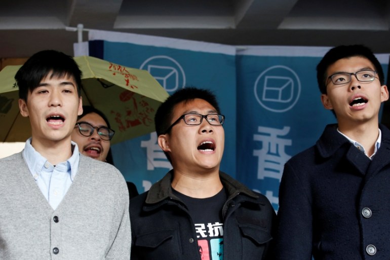 Pro-democracy activists (L-R) Lester Shum, Raphael Wong and Joshua Wong chant slogans outside High Court before receiving their sentences in Hong Kong
