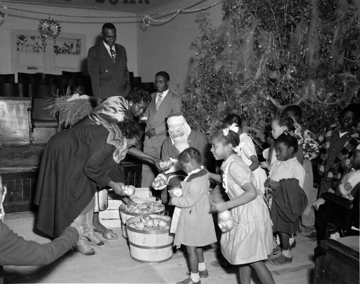 3: A man dressed as Santa Claus handing out Christmas gifts to children at a Fort Worth church in 1952. Unlike many segregated cities, where blacks lived only in one section, blacks in Fort Worth live