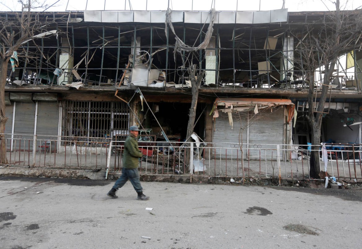 A member of Afghan security forces walks past a building damaged by Saturday''s suicide attack in Kabul, Afghanistan. REUTERS/Omar Sobhani